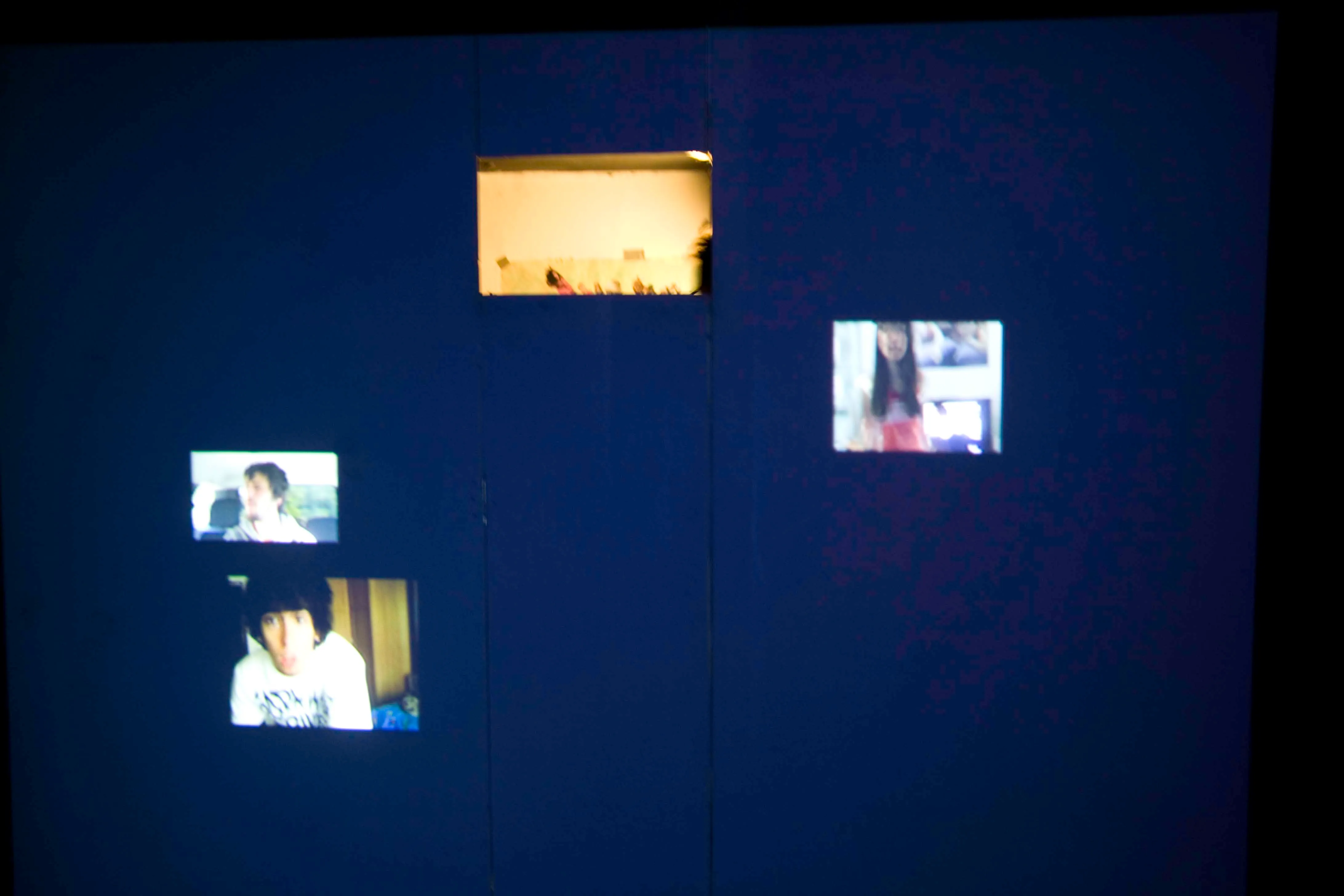 Installation view at night: projection wall pierced by the window
